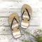 Tan flip-flops with white striped accents on a weathered wooden surface.