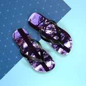 Flip-flops with a dark tree silhouette reflection on a blue geometric background.
