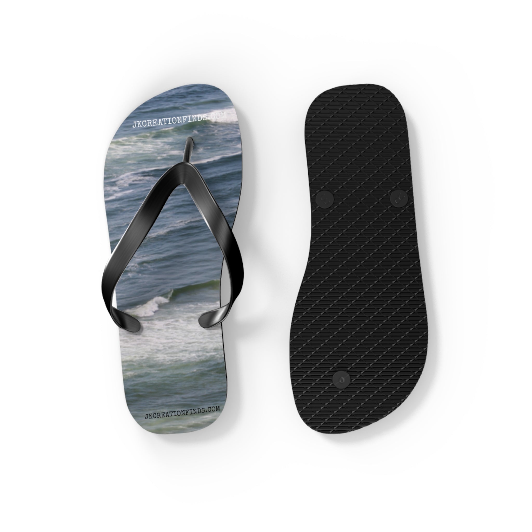 Black flip-flops with ocean wave print on one sole.