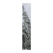 Tall snow-covered evergreen tree against a white sky.