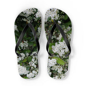 White floral pattern on black flip-flops with white soles.