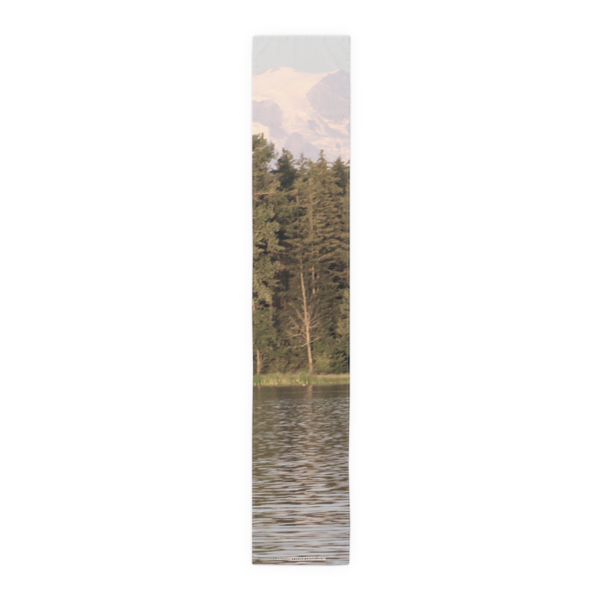 Tall pine trees reflected in water with snowy mountains above.