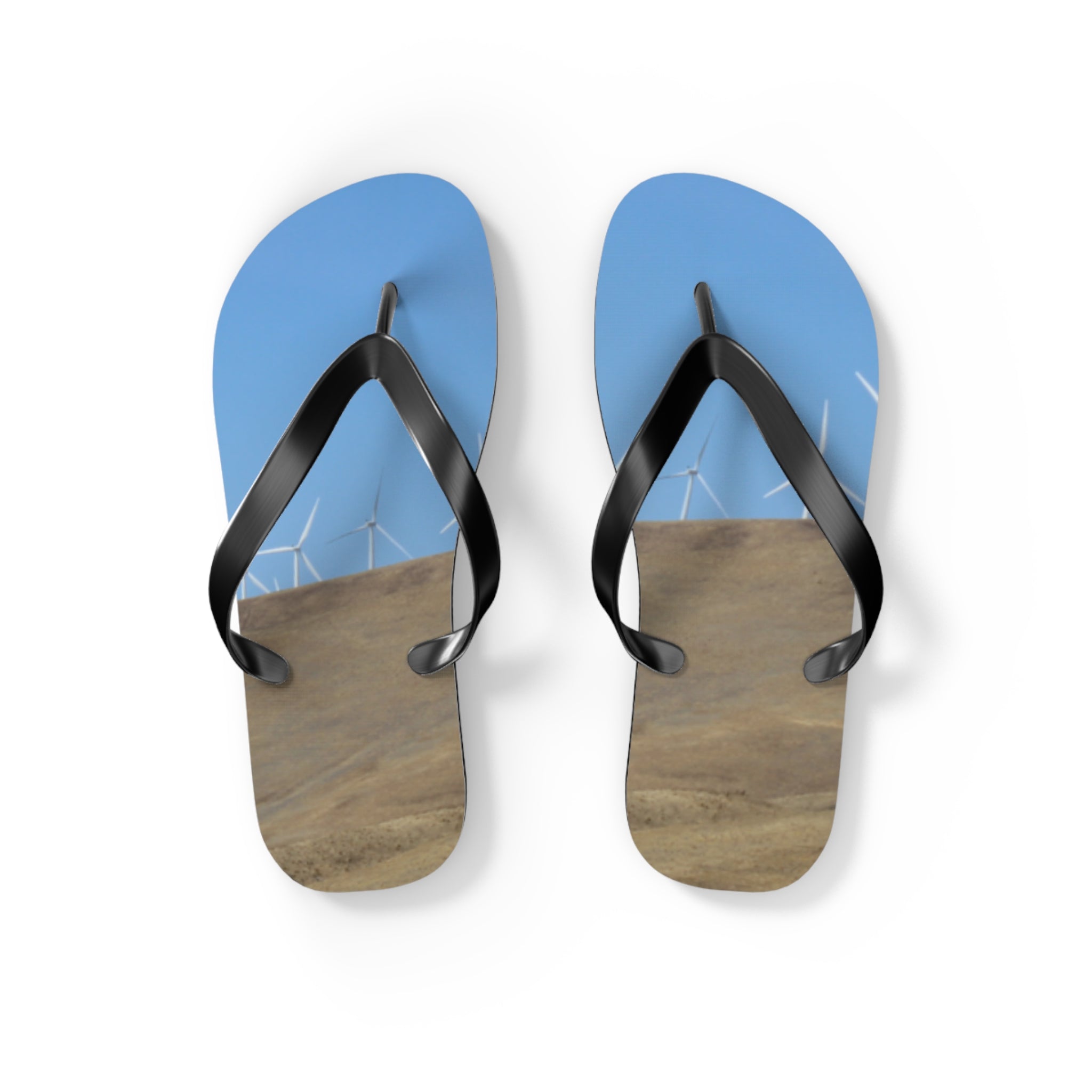 Flip-flops with wind turbines on a grassy hill and blue sky.