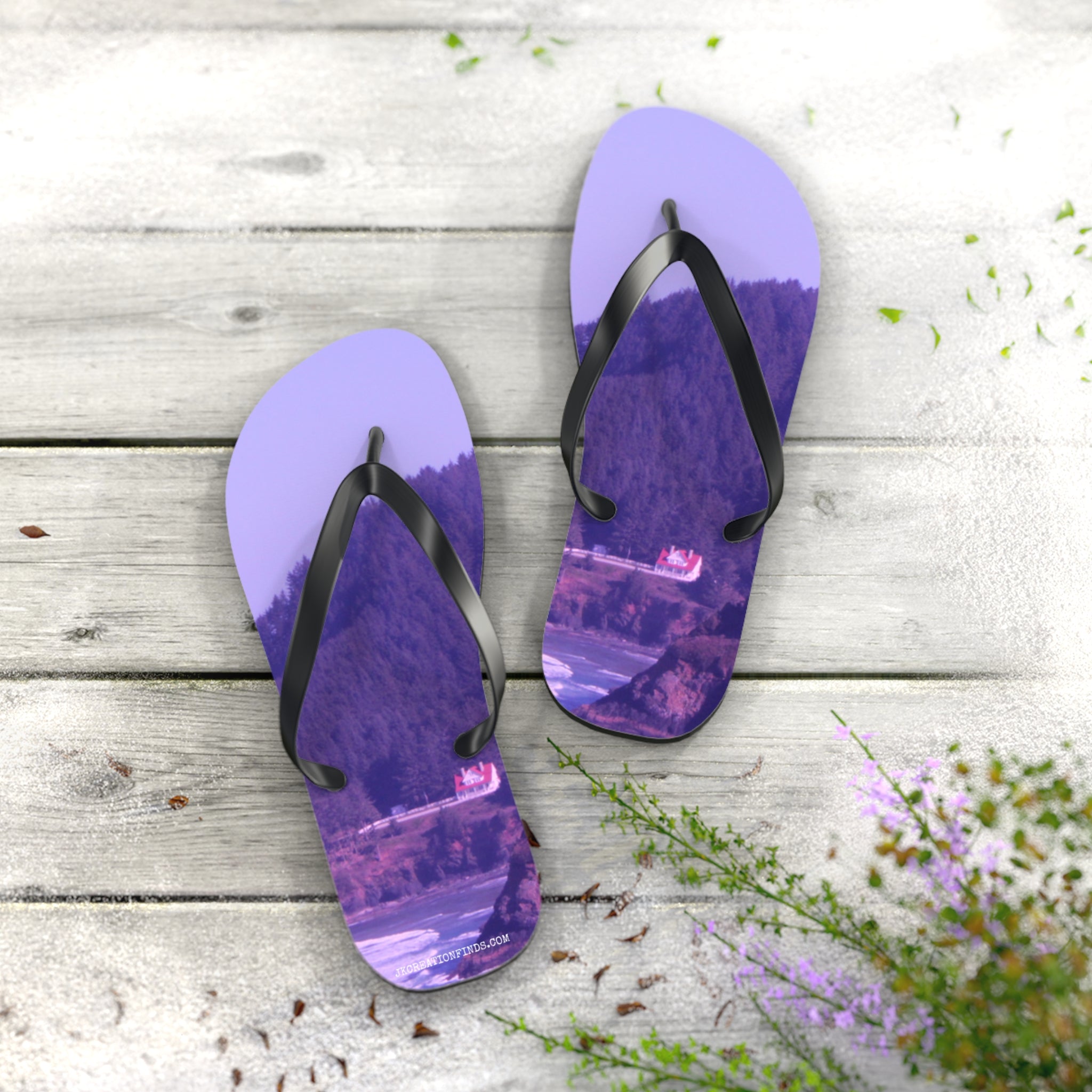 Purple flip-flops with a landscape print on a wooden surface.