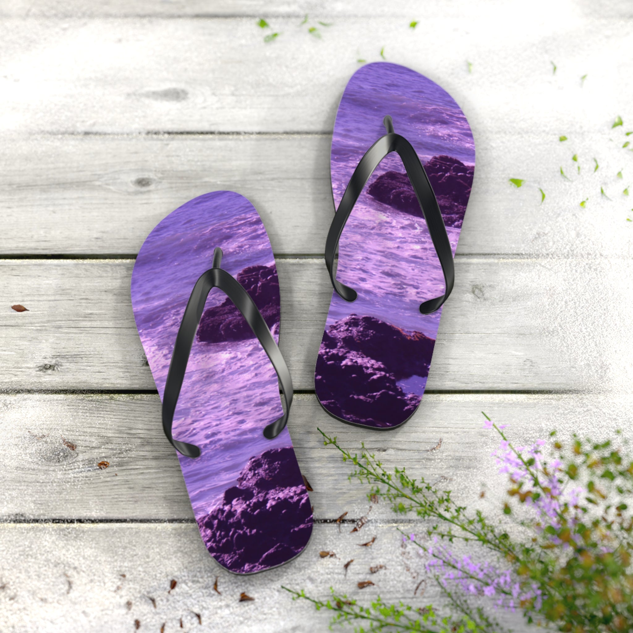 Purple flip-flops with ocean and rock scene on a wooden surface.