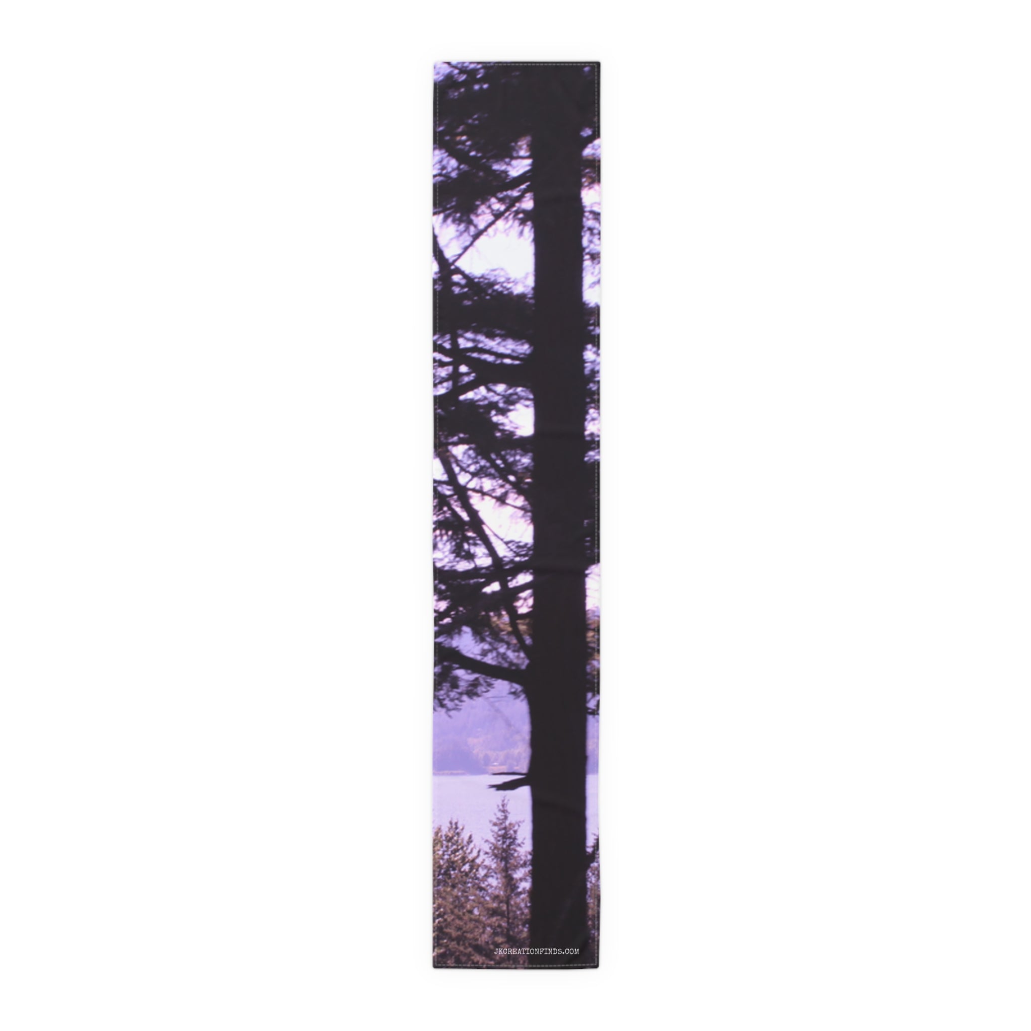 Tall pine tree silhouetted against a purple sky and distant lake.