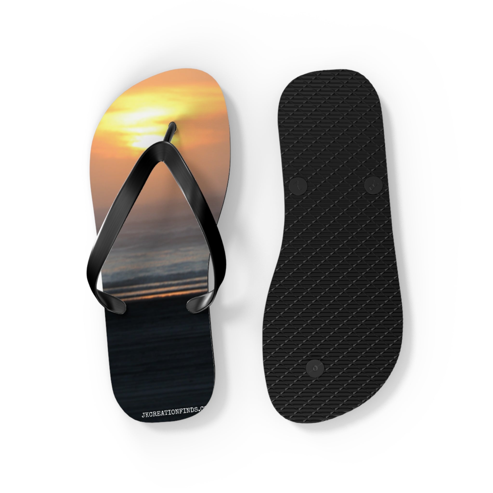 Black flip-flops with a sunset beach scene on the footbed.